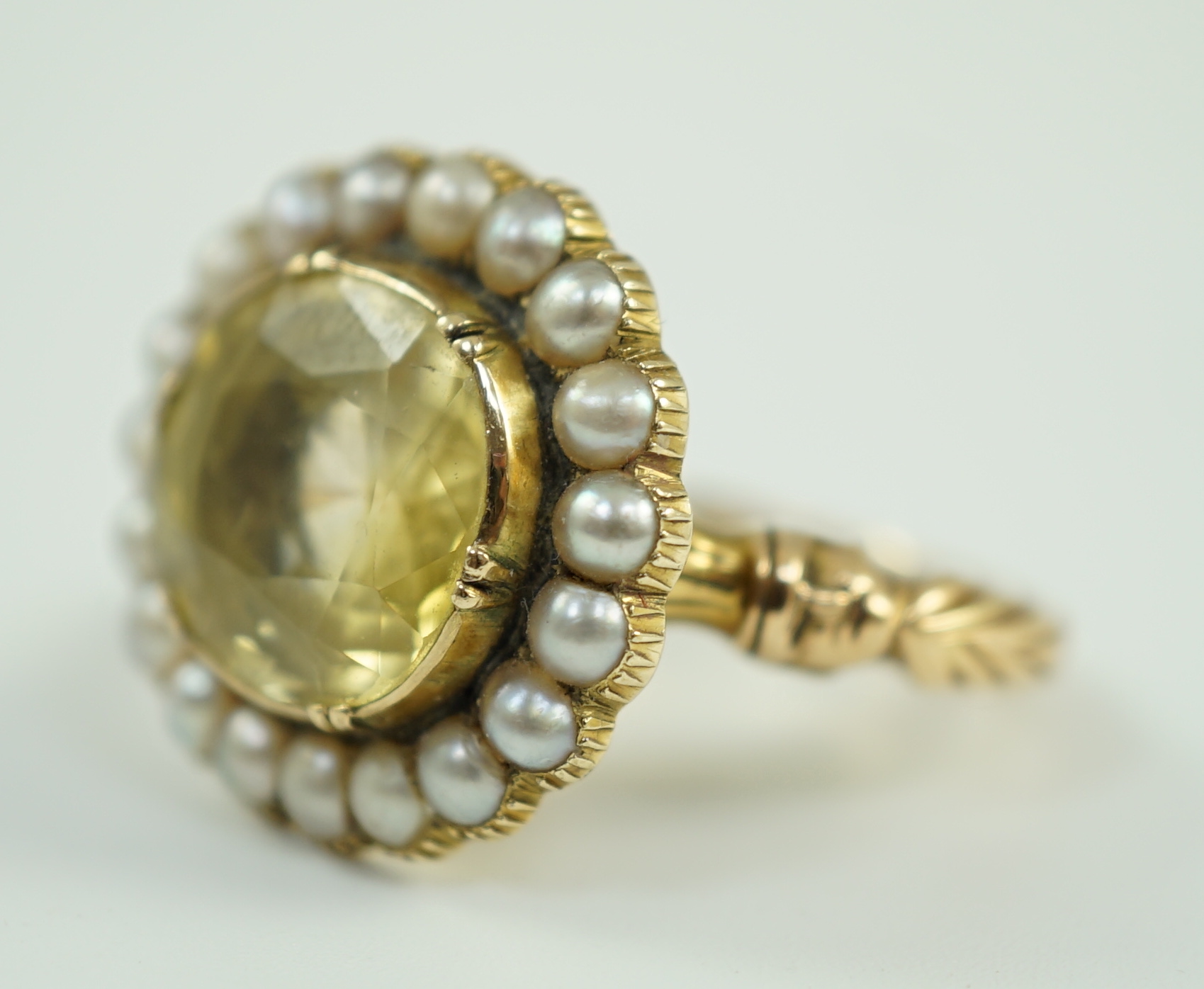 A 19th century style gold and round cut single stone yellow sapphire set dress ring, with split pearl set border